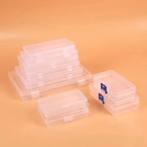 Stack of multi-grid clear plastic storage boxes with blue clips on orange background