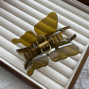 Close-up of translucent amber butterfly hair claw clip with golden metal spring