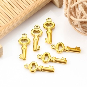 Set of 6 gold stainless steel key pendants for DIY jewelry making on white surface