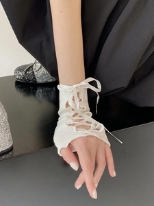 Dettaglio manica in maglia bianca con lacci, scaldabraccia con nastro stile dolce e cool.