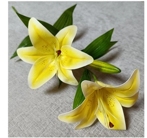 Macro shot of 3D artificial lilies with realistic yellow-white petals and green leaves