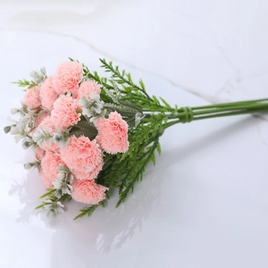 Top-down view of pink silk carnation bouquet on white tile background with clear reflection