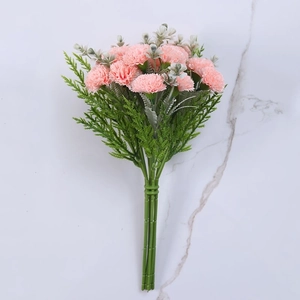 Detail of pink silk carnations with green pine needles on white marble background