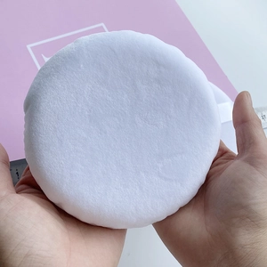 Detailed shot of an extra-large 27cm white velvet powder puff held by both hands