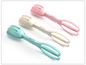 Three wheat straw salad tongs in pink, beige, and green colors on a white background