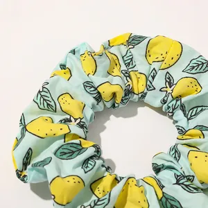 Detailed close-up of a blue fabric scrunchie with yellow lemon and green leaf prints