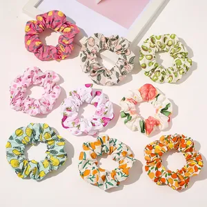 Flat lay of nine colorful fruit pattern fabric scrunchies on a white background