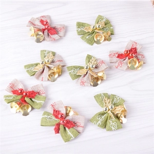 Red and green Christmas bows with golden bells and Merry Christmas print on wooden surface