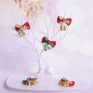 Christmas bow ornaments with holly leaves and gold bells on a white reindeer antler stand