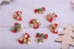 Detail of eight red fabric Christmas bows with gold bells and green leaves on wood