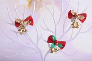 Detailed view of red Christmas bow ornaments with gold bells hanging on a white tree stand