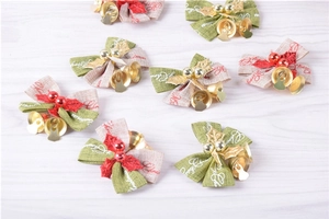 Flat lay view of mini Christmas bows with golden bells and red berries on wooden desk