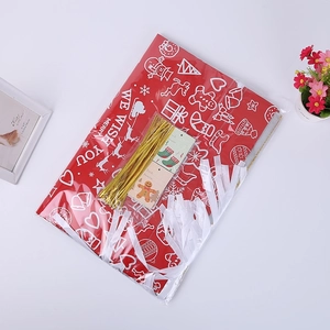Detail of red Christmas drawstring gift bag with festive patterns, tags, and golden ties