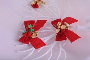 Close-up of red festive Christmas bow with gold bells and holly leaves on a white branch