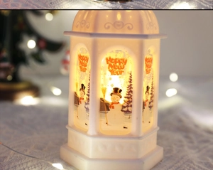 Detail of white Christmas lantern with snowman pattern and warm yellow glowing light