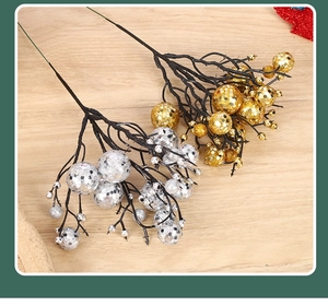 Close-up of sparkling gold and silver artificial berry stems on a rustic wooden table
