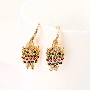 Colorful rhinestone owl hoop earrings in gold finish hanging on white ceramic cup