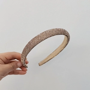 Macro detail of high-end champagne gold rhinestone headband with luxury padded design