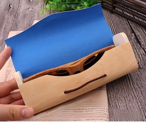 Detail of wooden glasses case with blue velvet lining and sunglasses on wood background