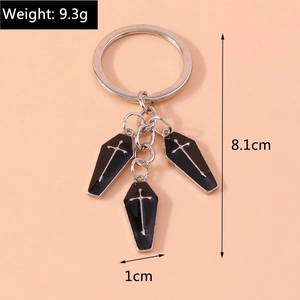 Gothic keychain detail showing three black coffin pendants with silver cross on peach background