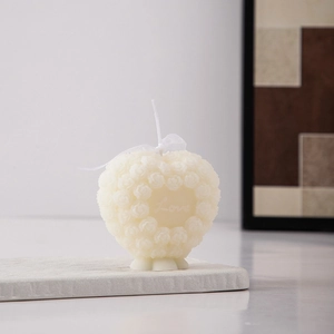 Detail of heart-shaped rose scented candle in creamy white with Love engraving
