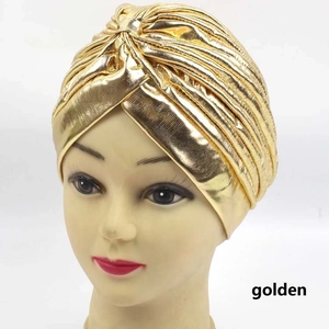 Close-up of golden metallic turban hat on mannequin head showing shiny fabric texture