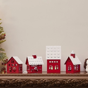 Set of four red iron Christmas house candle holders with snowy roofs on a mantelpiece