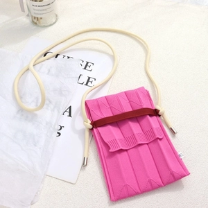Detailed view of pink knitted pleated phone bag with beige shoulder strap and texture