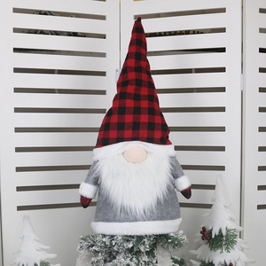 Red and black plaid Christmas gnome topper on a snowy tree for festive home decor
