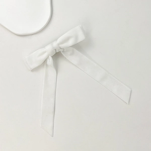 Detailed view of white satin bow hair clip with elegant long ribbon on a clean background