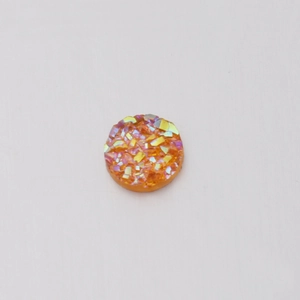 Detailed view of 6mm orange resin rhinestone with shimmering iridescent crystal texture