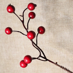 Close-up of artificial red berries on spiked stems over beige burlap fabric texture