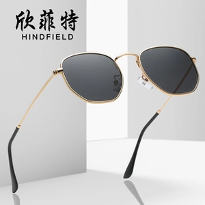 Detail of gold metal hexagonal sunglasses with dark grey lenses and realistic shadow