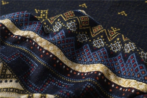 Macro detail of geometric tribal knit pattern on warm winter scarf with gold metallic threads