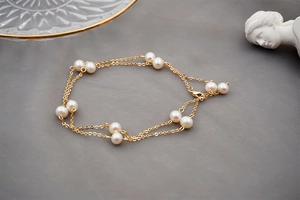 Detail of double-layer gold chain bracelet with freshwater pearls and lobster clasp