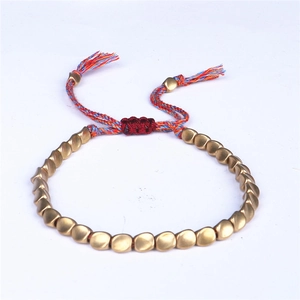 Dettaglio del bracciale intrecciato regolabile con perline dorate opache e corda colorata