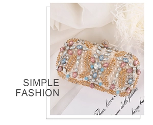 Detailed macro view of colorful rhinestones and gold leaf beadwork on beige clutch bag