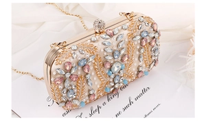 Close-up of golden clutch bag featuring intricate crystal leaf patterns and chain strap