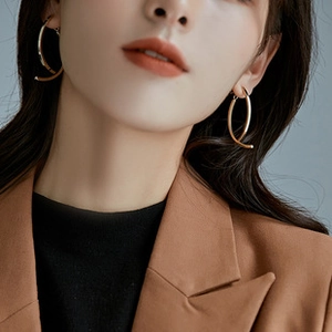Detailed view of elegant gold leaf hoop earrings worn by a model in a minimalist style