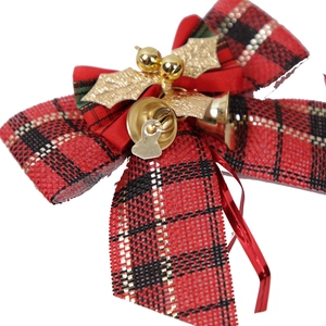 Close-up of red plaid Christmas bow with golden bells and holly leaf decorations