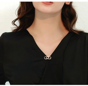 Silver rhinestone brooch pin with oval interlocking design shown on black V-neck top