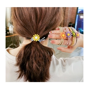 Detail of colorful daisy flower hair ties worn on wrist showing elastic multi-cord design