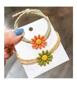 Detail of two-piece daisy hair ties in pastel green and yellow with resin flowers