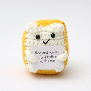 Close-up of handmade crochet toast doll holding a card with English positive quote