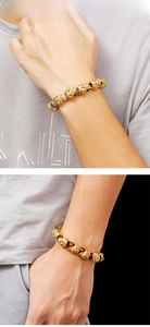 Detail of men's beaded bracelet with golden skulls and tiger eye stones on wrist