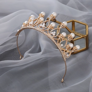 Detail of a golden crown with pearls and crystals on soft grey mesh fabric