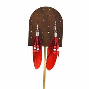 Close-up of red feather earrings with bead accents and ethnic bohemian style detail