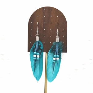 Detail of turquoise feather earrings with bohemian beads on a wooden display stand