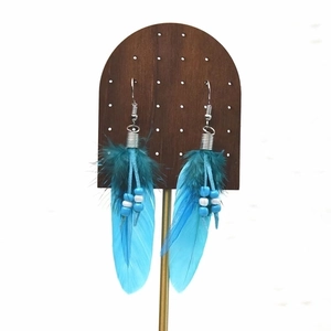 Detail of bohemian long feather tassel earrings with blue beads on wooden display stand