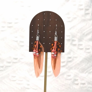 Close-up of bohemian long feather earrings with warm orange tones and delicate beadwork